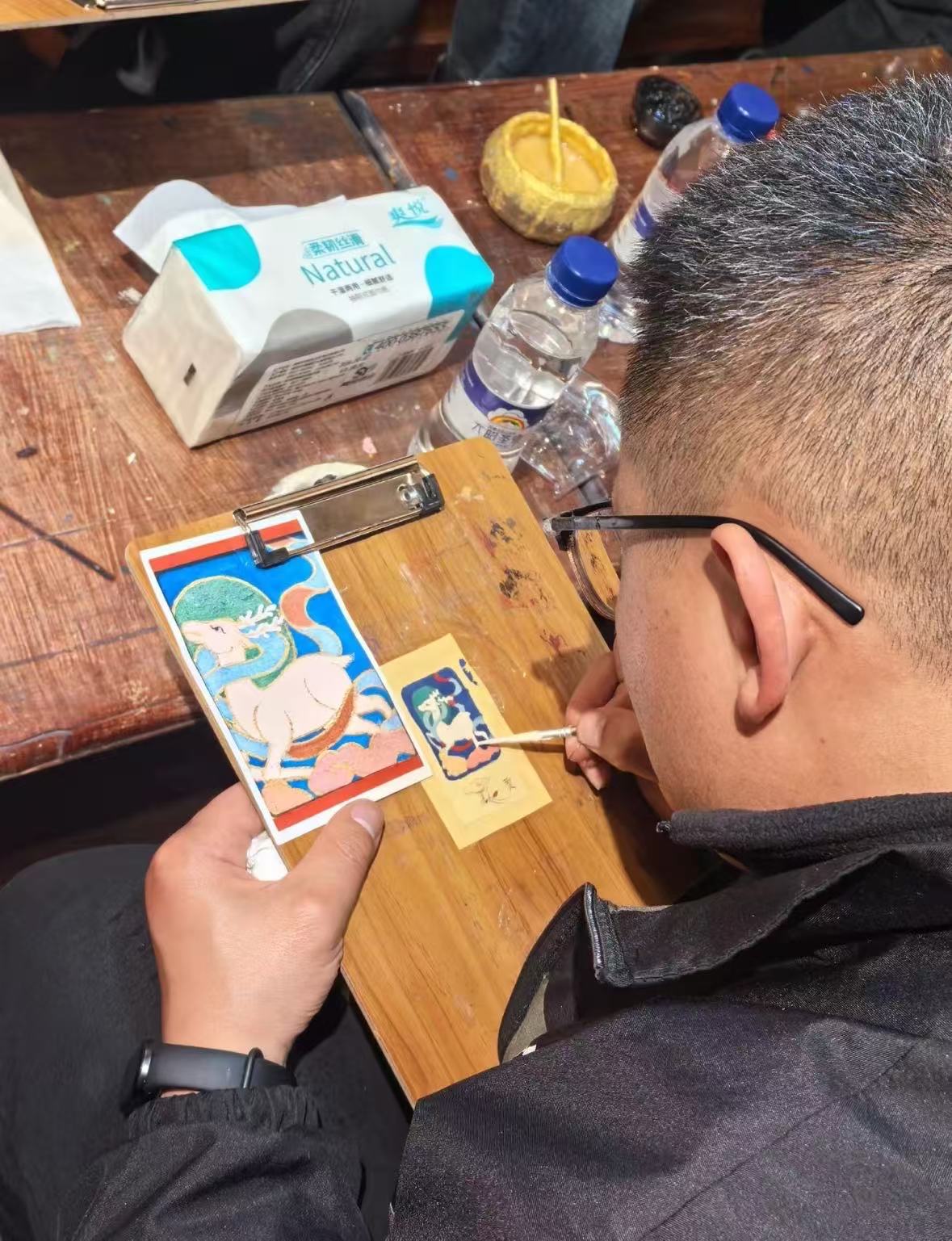 体验者对照彩色图样,用细笔在画板上绘制图案