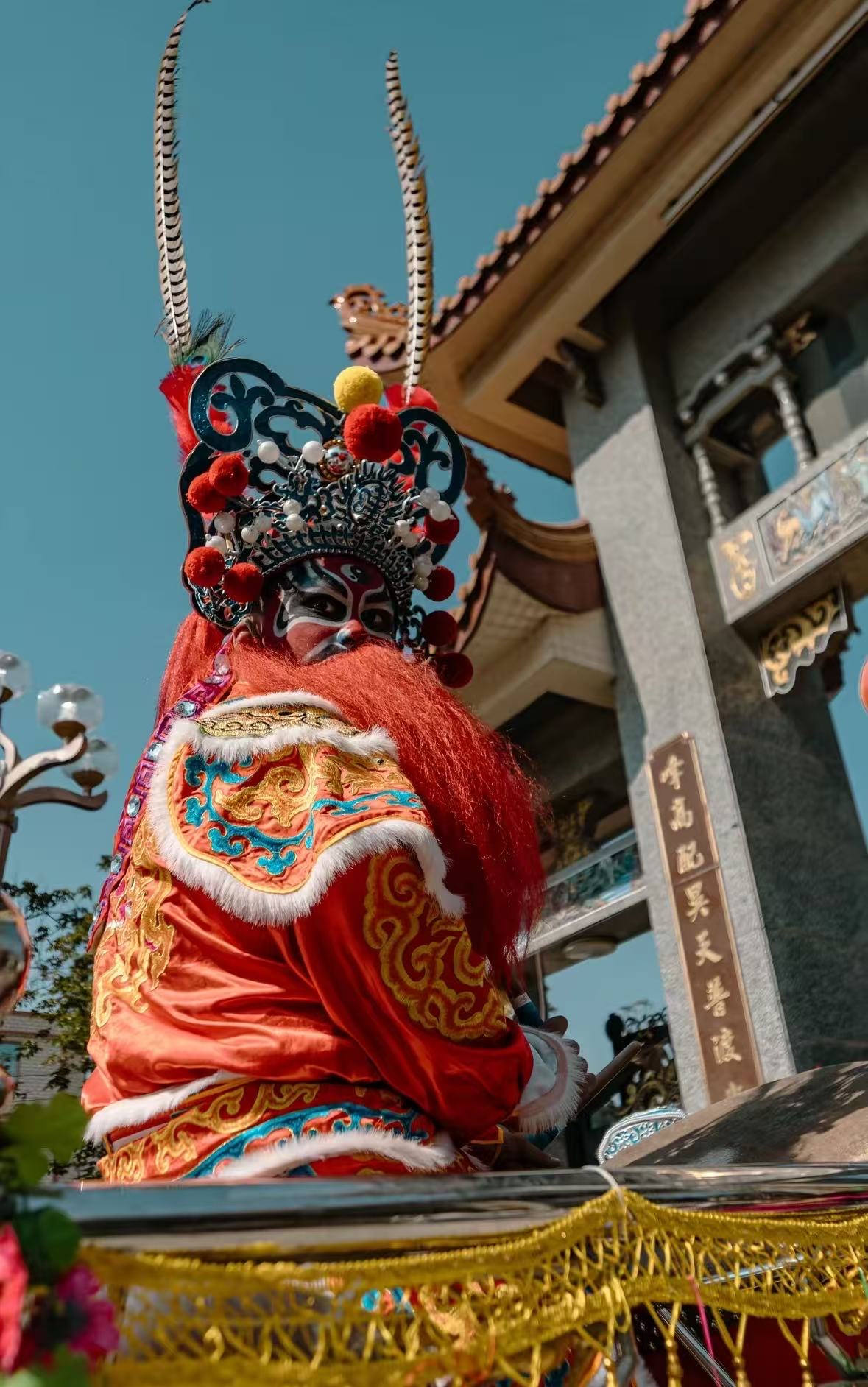 身着红色传统戏服的表演者与庙宇